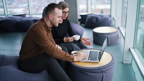 Two smiling creative workers discussing project during meeting in cafe