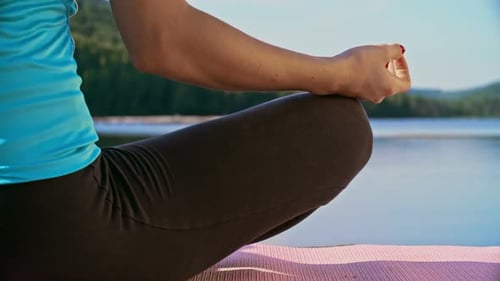 Woman Meditating Outdoors By A Serene Lake