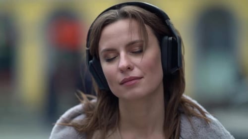 Woman Listening to Music on Headphones in City