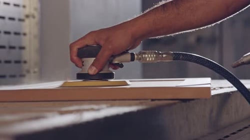Slow motion of a worker polishing a cabinet door in a furniture factory