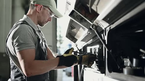 Man Repairing Truck Engine in Automotive Shop
