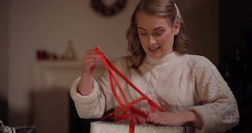 Woman Smiles Opening Christmas Gift at Home