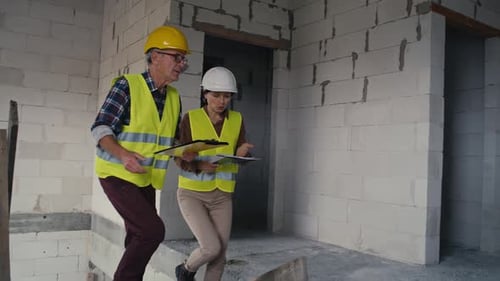 Male and female caucasian engineers talking while walking up on stairs
