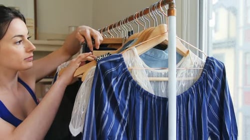 Woman Sorting Clothes on Rack in Home