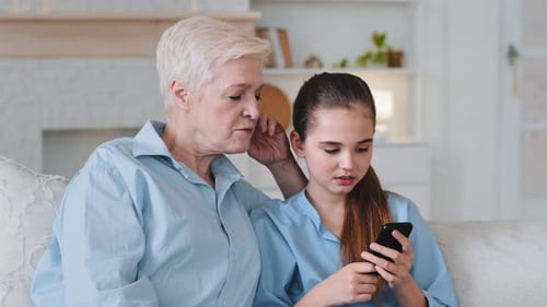 Grandmother and Granddaughter Using Smartphone Together at Home