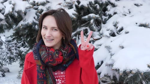 Smiling Woman Makes Peace Sign in Winter Scene