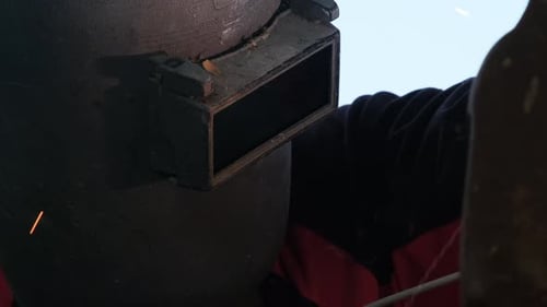 Erfahrene Metallarbeiter mit Schweißmasken und Handschuhen arbeiten in der Heimwerkstatt