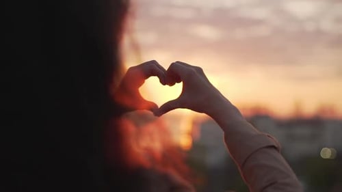 Woman Creates Heart Shape with Sunset