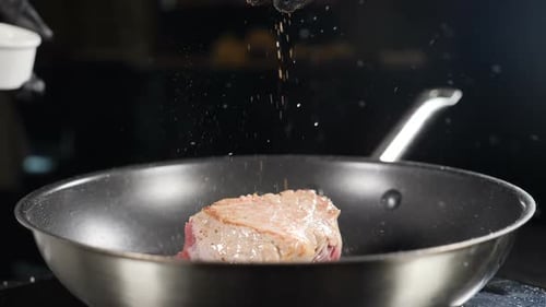 Seasoning Delicious Steak in Frying Pan Close Up