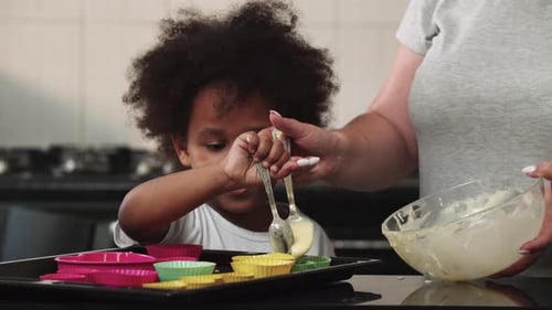 Gemischte Familienherstellung Cupcakes, die rohen flüssigen Teig in die Kuchenformen gießen