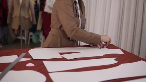 Professional Female Tailor is Working at Table with Red Cloth in Atelier