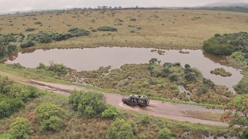 Four wheel drive vehicle driving through muddy puddle in Aberdare National Park, Kenya, Africa, Aerial