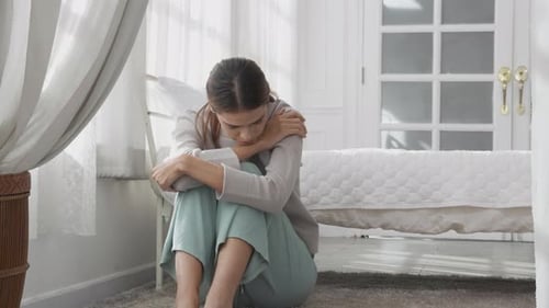 Woman Sitting on Bedroom Floor Contemplating