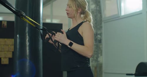 Determined Woman Training with Resistance Straps in Gym