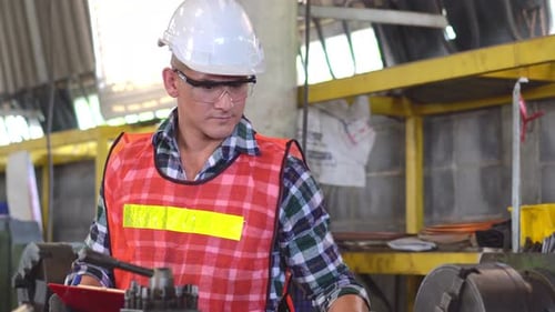 Engineer foreman with repair checklist working repair on machine at the factory