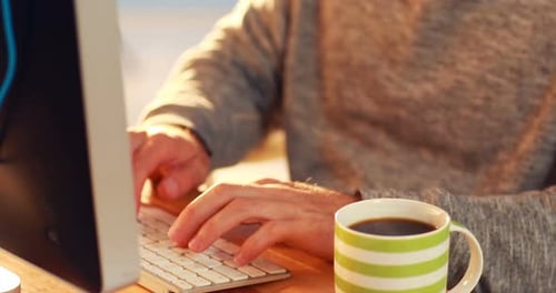 Business executive working on computer while having coffee
