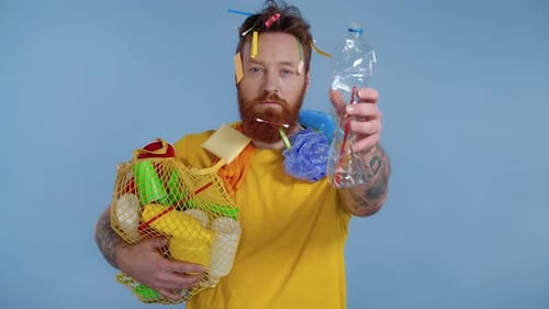 Man Holds Plastic Bottle and Net Bag with Recyclables