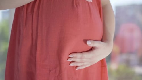 Young Female Hands Stroking Pregnant Belly. Angle View Close-up of Unrecognizable Caucasian
