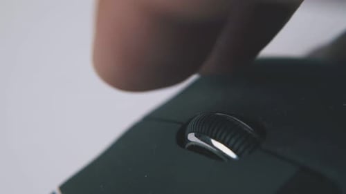 Man Scrolls Wheel of Computer Mouse on White Surface