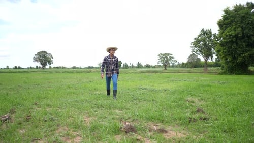 Farmer Walks Through Green Field on Sunny Day