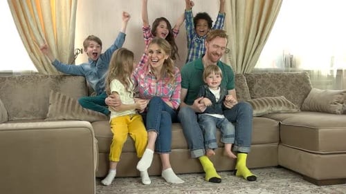Happy Family Cheering Together on Sofa in Living Room