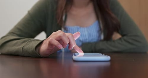 Person Using Smartphone at Table Indoors
