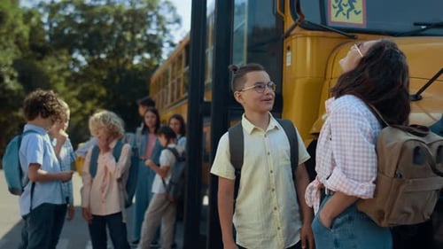 Two Pupils Stand Chatting at Schoolbus Waiting Bus Boarding