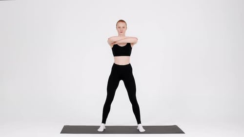 Fit Young Female Making Squats Exercise While Training In Studio