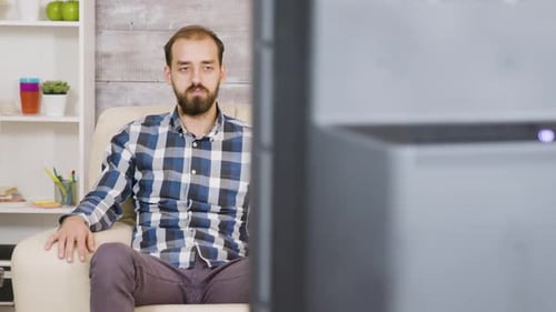 Man With Beard Relaxing on Couch Watching TV