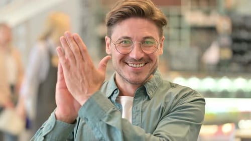 Man Smiling and Clapping in an Office Environment