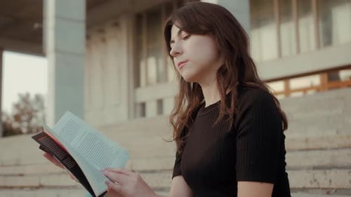 Young Woman Reading a Book on Stone Steps