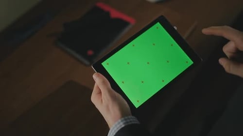 Male Hand Holding Tablet Pc with Green Screen. Closeup Man Swiping Tablet Screen