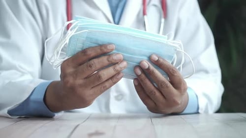 Doctor Holds Stack of Protective Face Masks