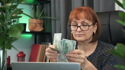 Woman Counting US Currency at Desk