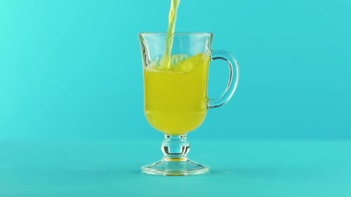 Slow Motion Close-up Shot of Fruit Fizzy Orange Soda Cold Beverage Drink Pooring Into Latte Glass