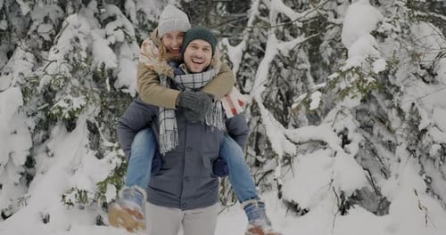 Slow Motion Portrait of Cute Couple Having Fun in Winter Forest Man Holding Woman in His Back