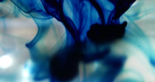 Macro shot of blue ink drops as it spreads out slowly underwater and creates smokey abstract shapes