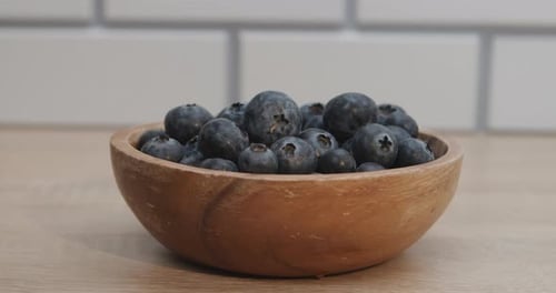 Hand Picks Up Blueberry from Bowl