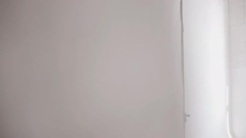 A Beautiful Young Girl in a Stretching Studio Moves Smoothly and Looks Out From Behind White Tulle