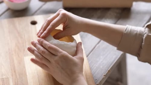 Hands Shaping Soft Clay Pottery on Wooden Table