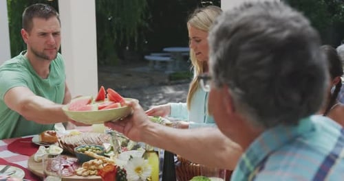 Family and Friends Enjoying Picnic Meal Together