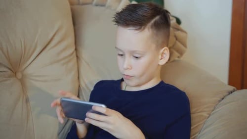 Boy Plays a Video Game on a Smartphone