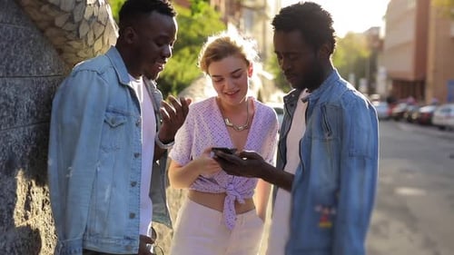 Three Friends Looking at Mobile Phone on Urban Street