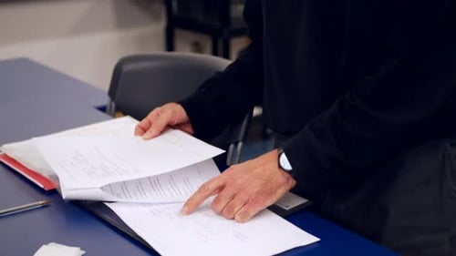 A college science professor grading a midterm test from his students and taking notes in a binder du