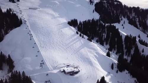 Aerial view smoothement along the ski slopes in the ski resort. Magnificent snowy mountains and blue