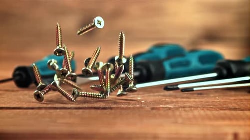 Screws Falling on Wooden Surface with Screwdrivers