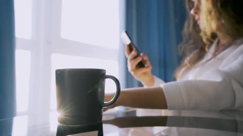 Young Woman Relaxing at Home with Coffee and Phone