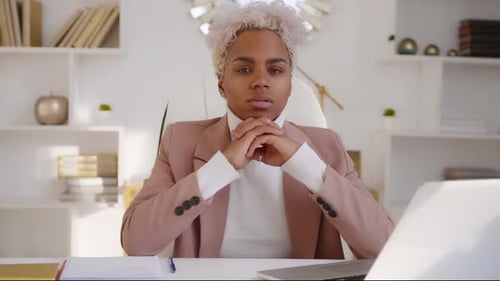 Young African American Woman Entrepreneur Looking at Camera Sits at Office Desk