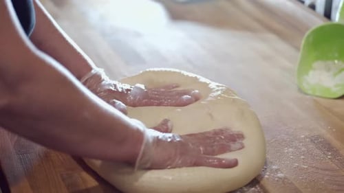 Adult Kneading Dough with Rolling Pin on Wooden Counter