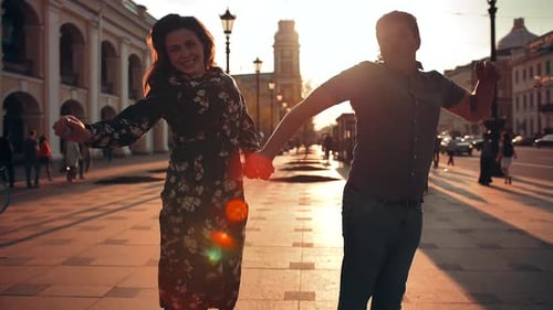 Playful Happy Young Couple Is Jumping Down the Street and Laughing.